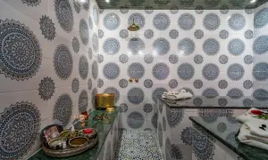 Ett vackert hammam i Marrakech med traditionella mönster på väggarna och golvet. En gyllene skål och skönhetsprodukter står redo för en avkopplande upplevelse.