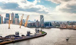 En linbana London över Themsen, med O2 Arena och skyskrapor i bakgrunden.