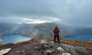Man på en klippa med en sjö och berg i bakgrunden. En lyckad trolltunga vandring!