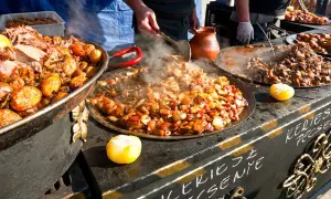 Varm mat ångar från stora pannor på en marknad i Budapest. Kött och grönsaker tillagas.