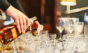 Händer häller upp whisky i små glas. En härlig whiskyprovning i Edinburgh väntar.