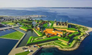 Kronborgs slott vid sundet, en del av Danmarks natur, med en stor marina och grönskande vallgravar.