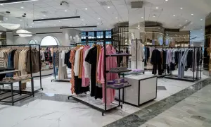 En modern klädbutik med kläder på galgar och hyllor. En härlig shoppinggata Stockholm-känsla med stilrena inredningsdetaljer.