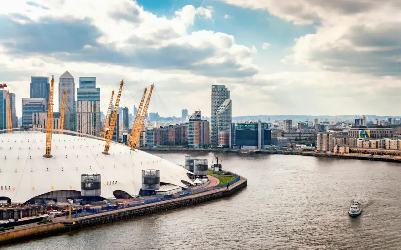 En linbana London över Themsen, med O2 Arena och skyskrapor i bakgrunden.