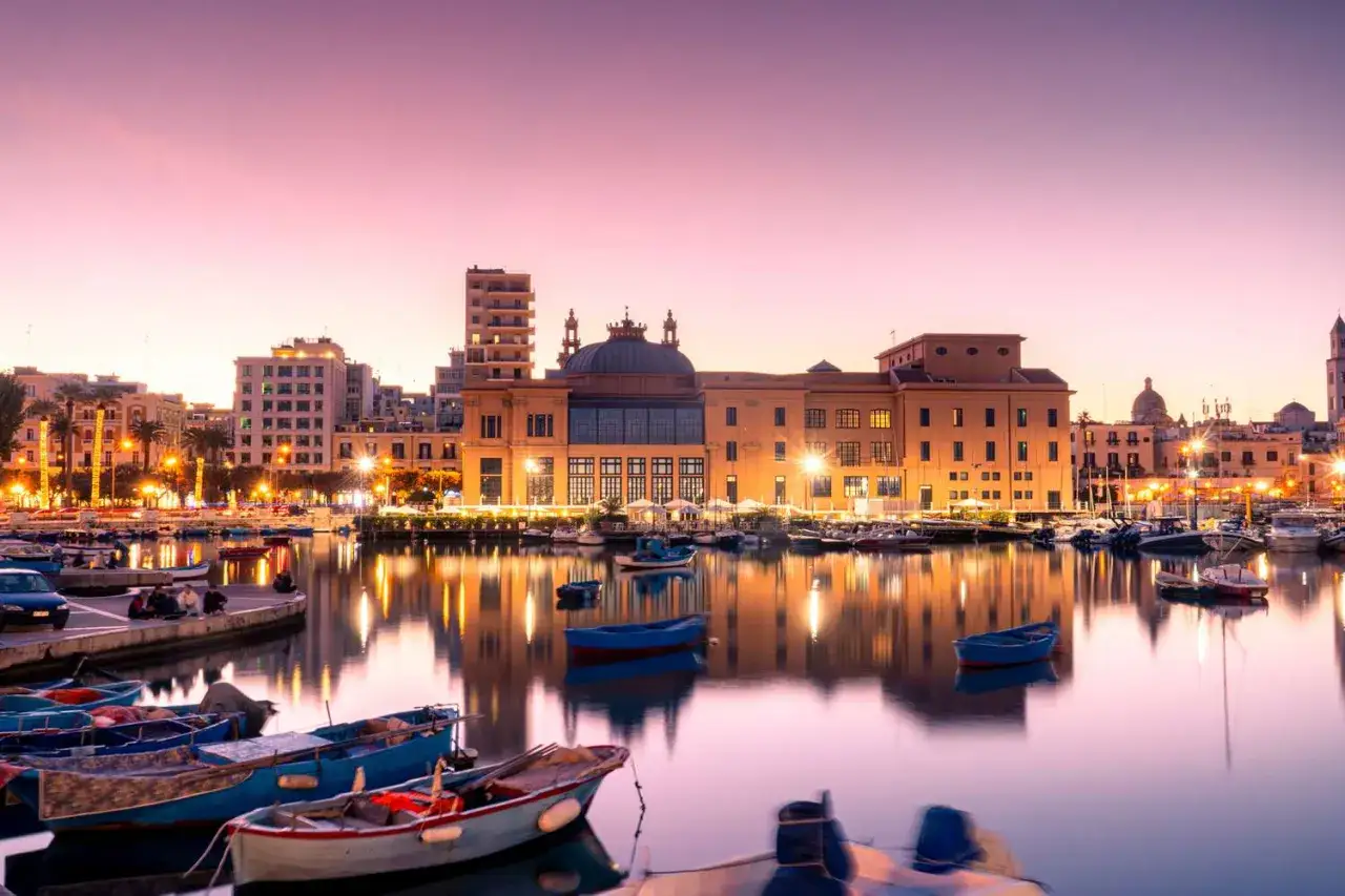 Båtar i hamnen i Bari, Italien, reflekteras i vattnet vid solnedgången.