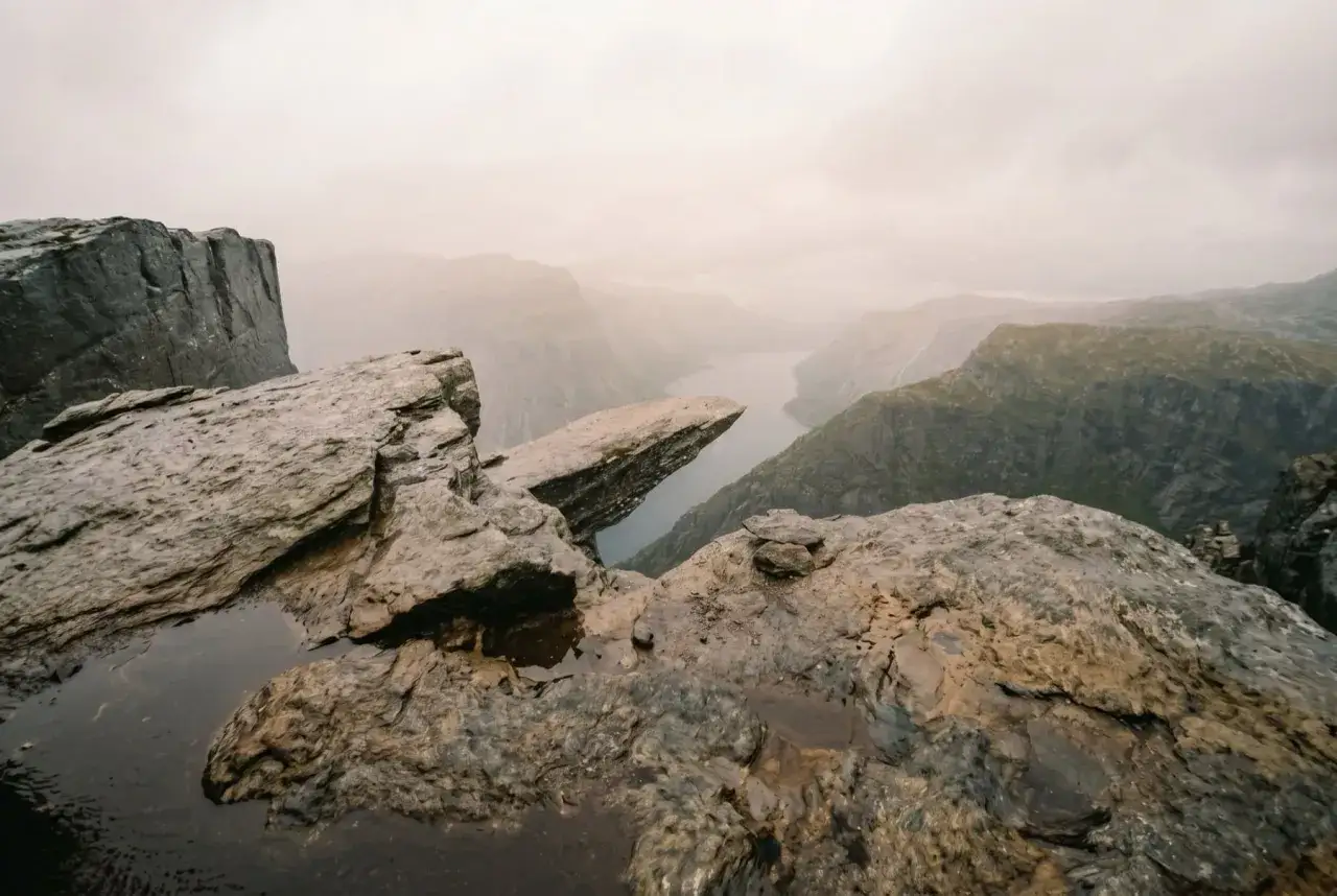 Trolltunga i Norge, en ikonisk klippa som sticker ut över en fjord. Dramatiskt landskap i dimma.
