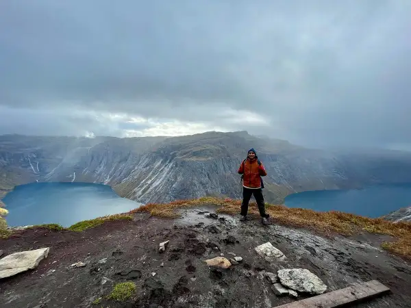 Man på en klippa med en sjö och berg i bakgrunden. En lyckad trolltunga vandring!