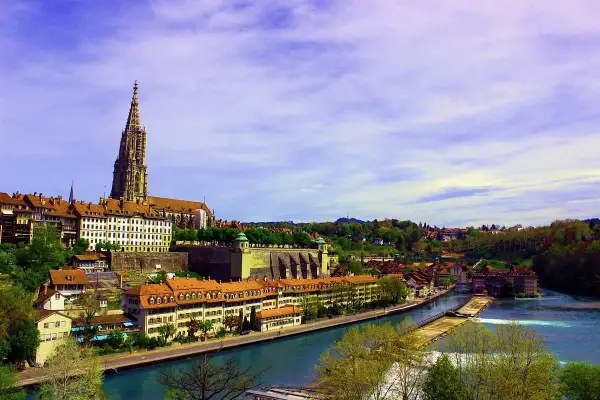 En vacker vy över en flod i Bern, med den imponerande Bern-katedralen som reser sig över stadens tak.